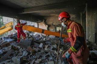 Rescuers search through the rubble of a damaged section of Evin Prison following an Israeli strike